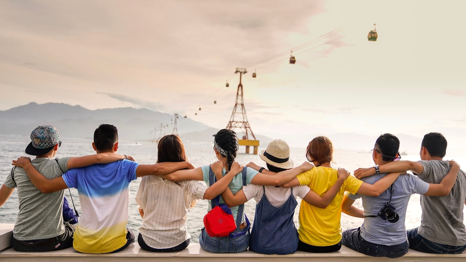 A group of friends with arms around each other looking out across the water